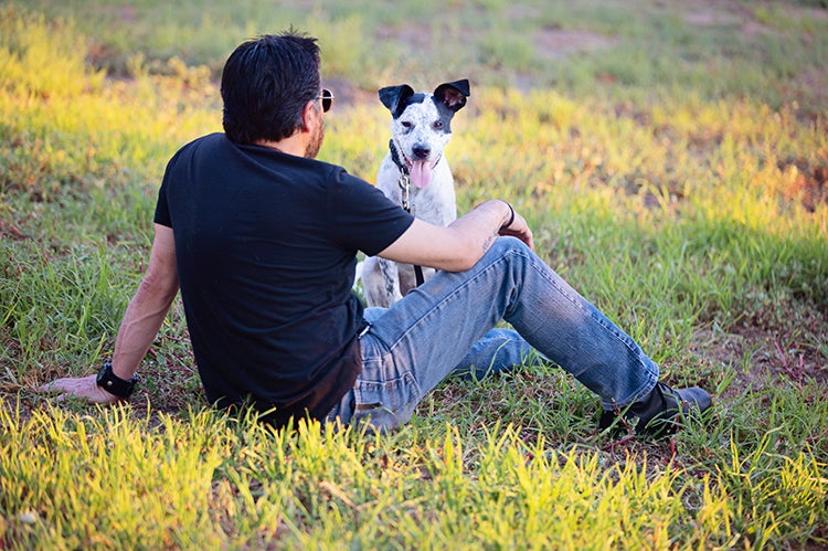 Man and dog lying outside on some green grass