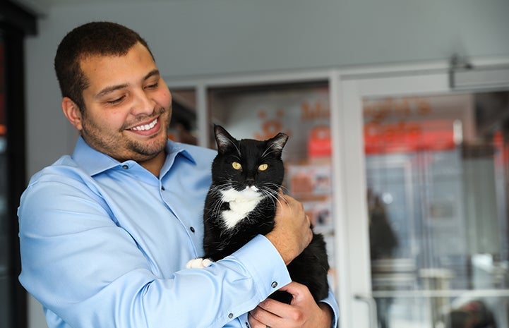 Smiling man holding a black and white cat