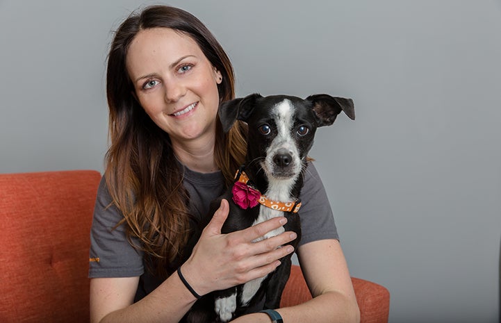 Woman holding a black and white dog wearing a Best Friends collar with a pink flower on it