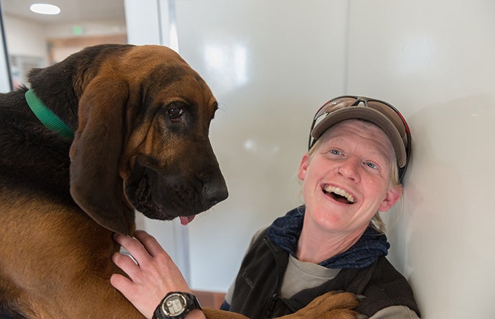 Woman laughing next to a big bloodhound dog named Luther
