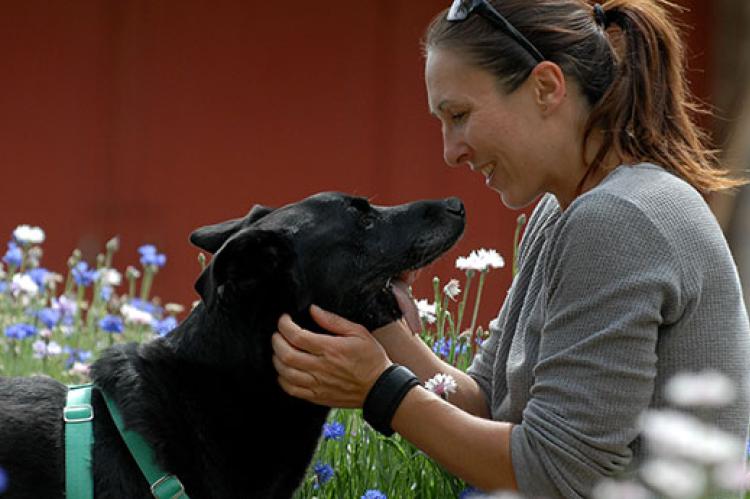 Woman with black special-needs Lab mix dog. She has affordable pet insurance to help with his vet bills.