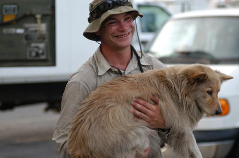 Ethan carrying a tan colored dog after rescuing him following a hurricane