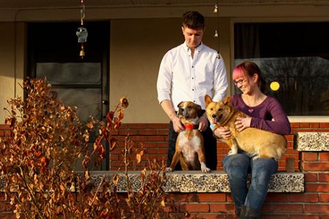 couple and two dogs in front of a pet-friendly rental house