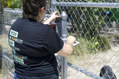 Woman placing a hanging notice on a chain link fence