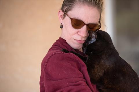 Person snuggling with a black cat
