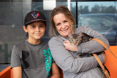 Smiling family adopting a tabby cat