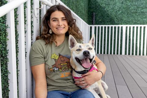 Smiling person hugging a smiling dog on a deck surrounded by a wood railing