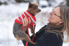 Woman holding a terrier dog wearing a red sweater